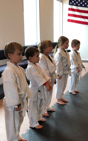 A preschool girl demonstrating a kick while enjoying karate.